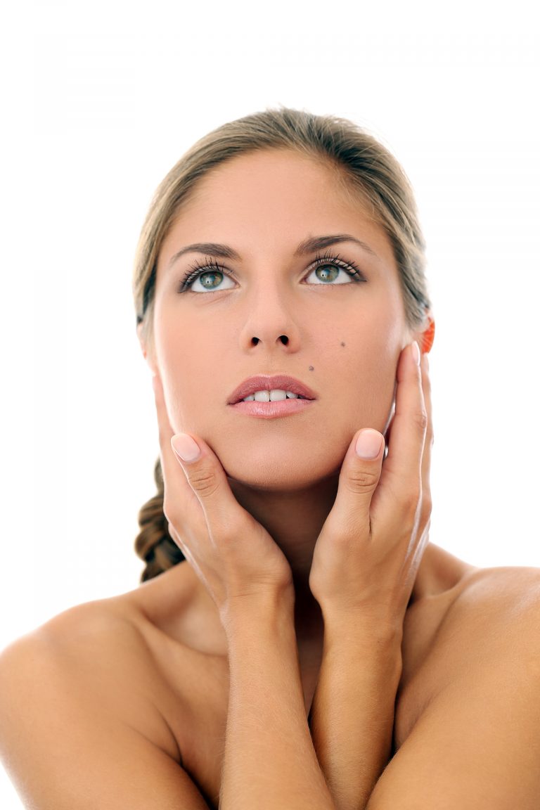 Portrait of a beautiful girl with a plait who is touching herself and posing over a white background